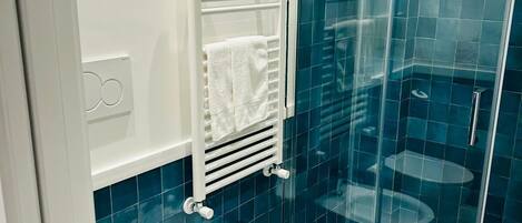 A modern bathroom with a glass shower enclosure, a white toilet, and a bidet.