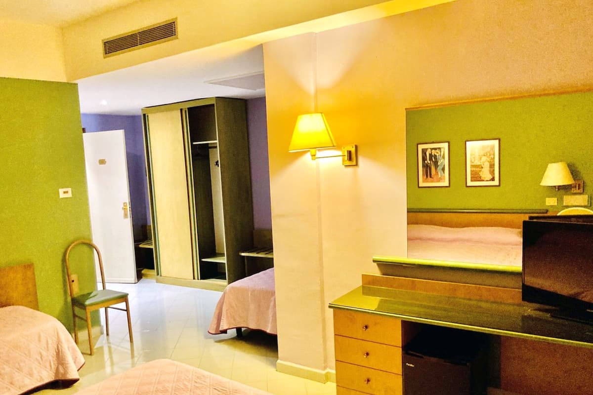 Een hotelkamer met twee bedden, een bureau, een stoel, een kledingkast en een televisie.