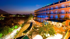 Un hotel con varios balcones, mobiliario exterior y vistas del paisaje circundante.