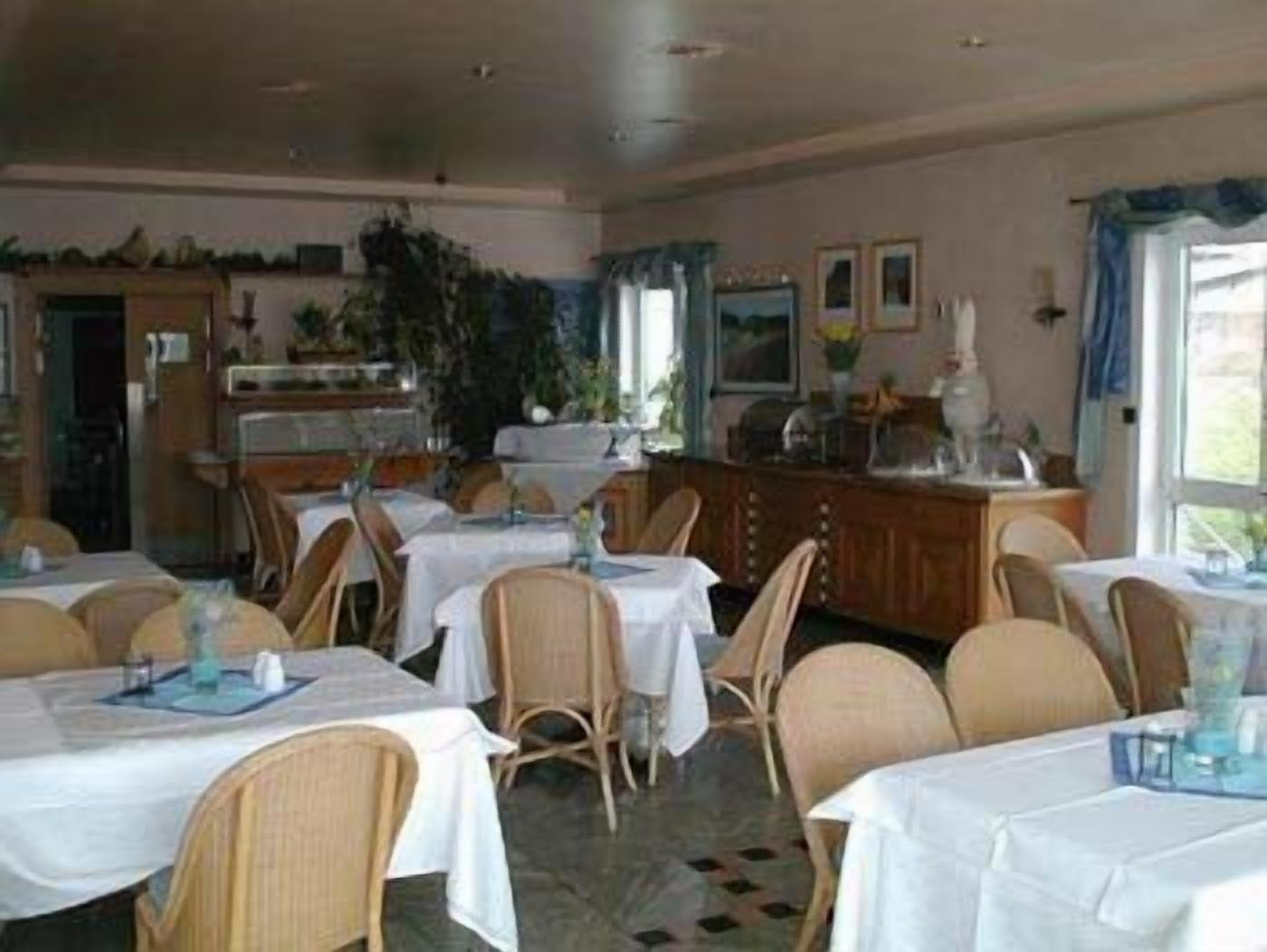A dining area with tables set for guests, chairs, and a counter with a display.
