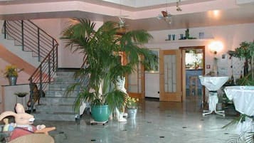 En rummelig lobby med marmorgulv, trappe og flere krukkeplanter.