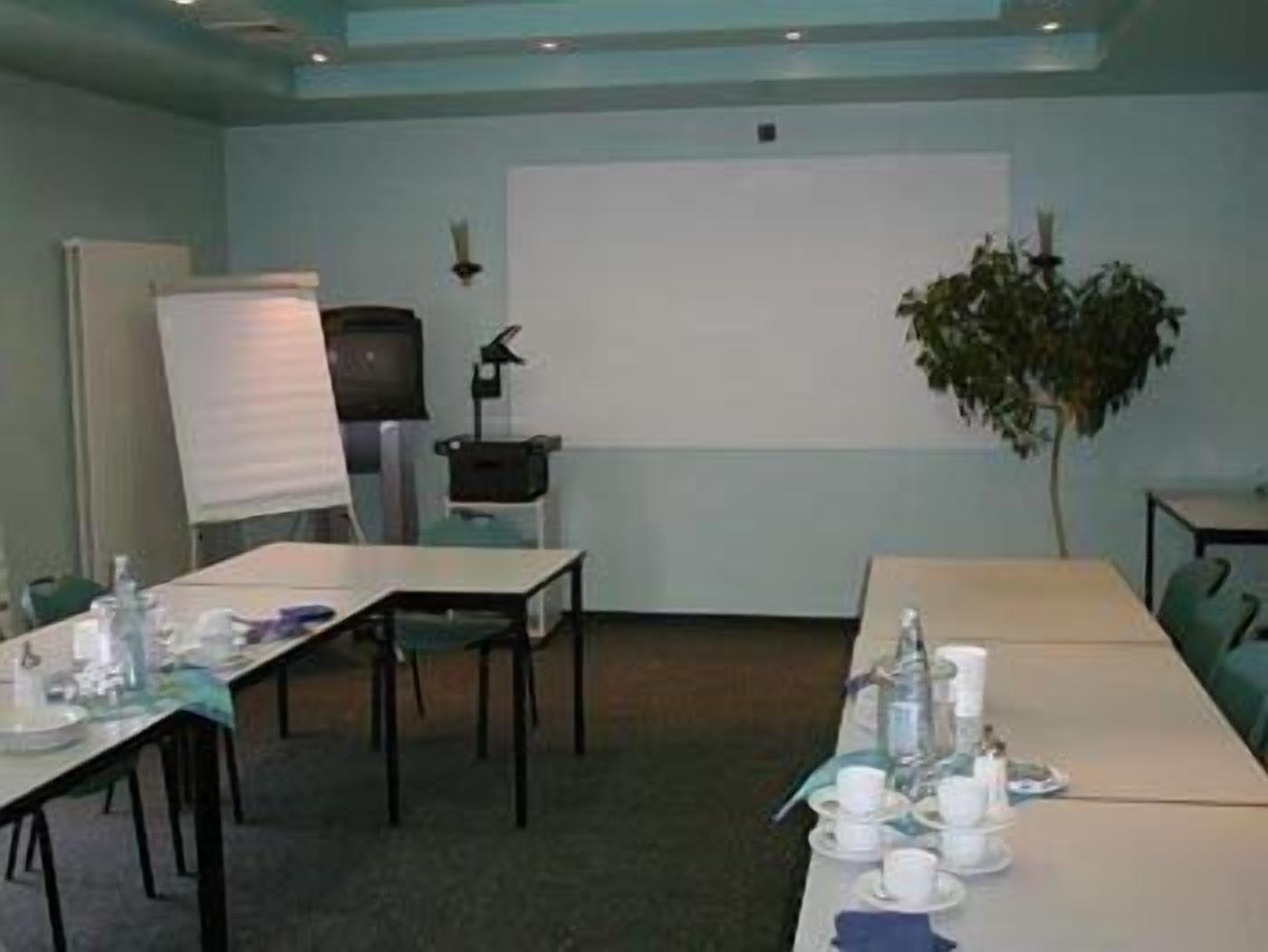 A conference room with a long table set for a meeting, a whiteboard, and a projector.