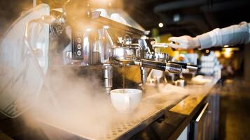 A coffee machine dispensing espresso into a cup, with steam rising from the process.