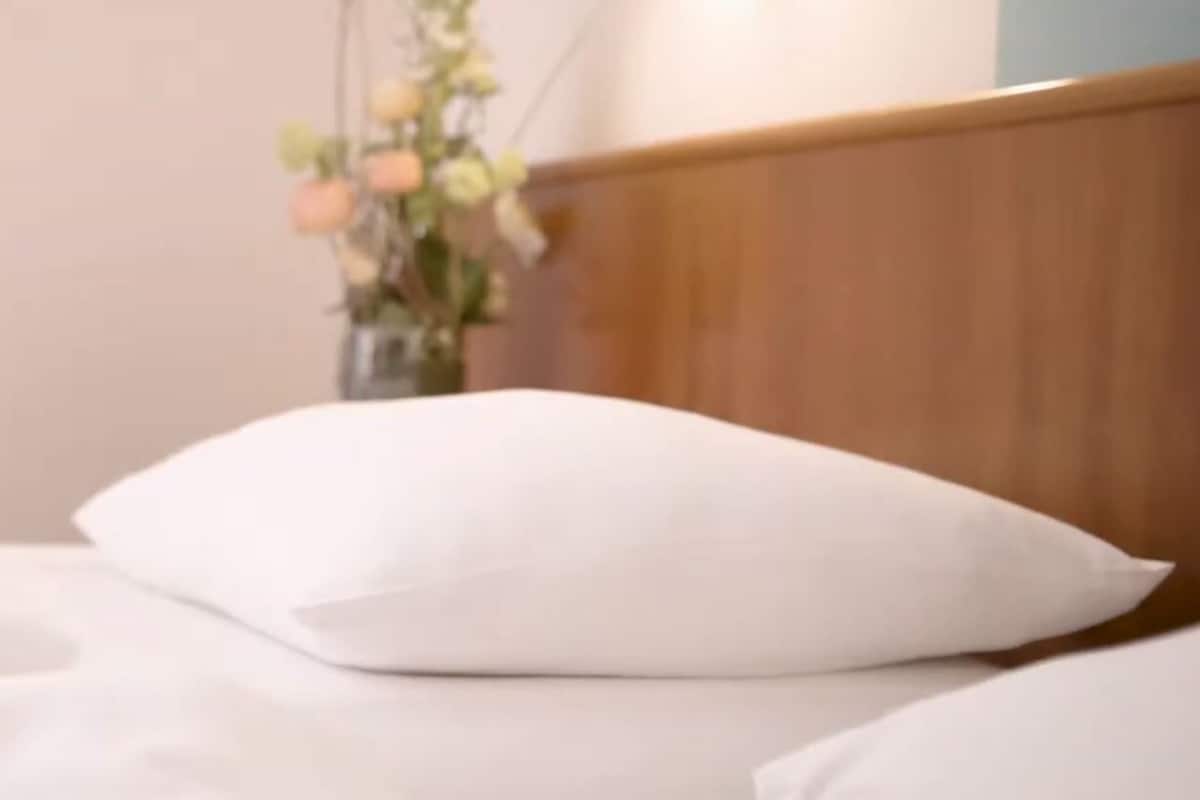 Ein Bett mit weißer Bettwäsche und einem Holz-Kopfteil.