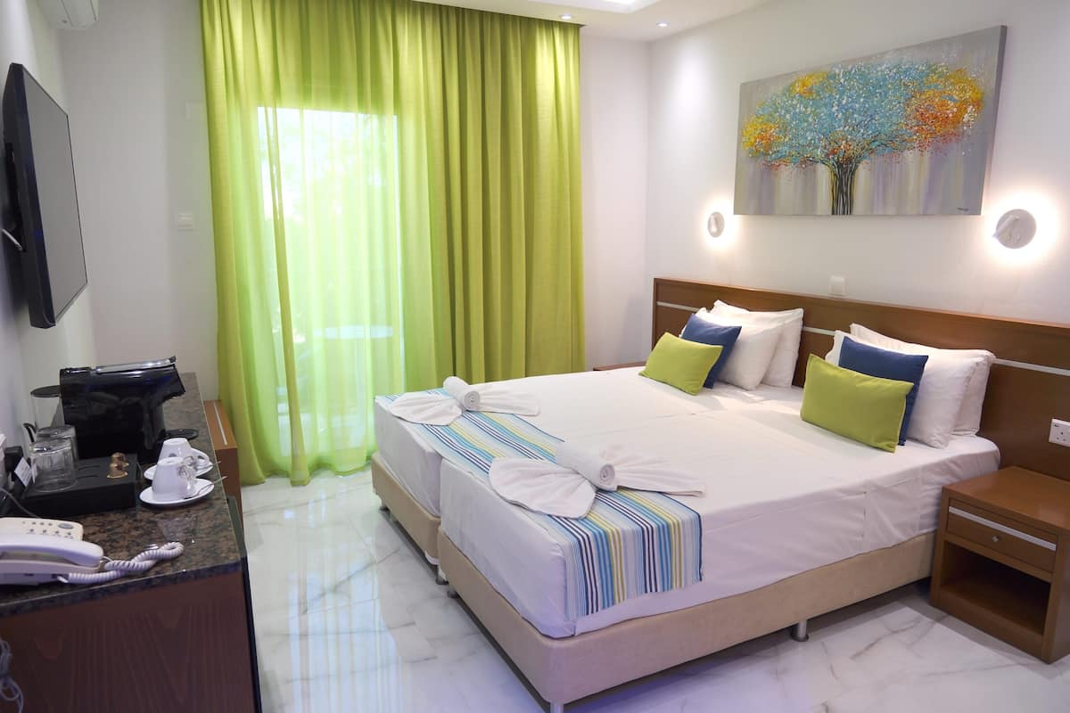 A hotel room with a bed, bedside tables, a desk with a telephone, and a painting on the wall.