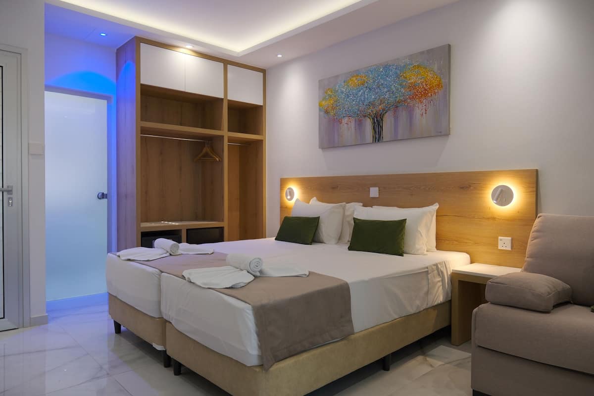 A hotel room with a large bed, a wooden headboard, a painting on the wall, and a seating area.