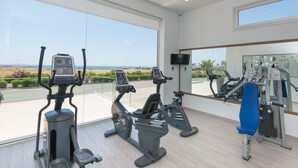 Academia com equipamento de exercícios e uma grande janela com vista para o exterior.