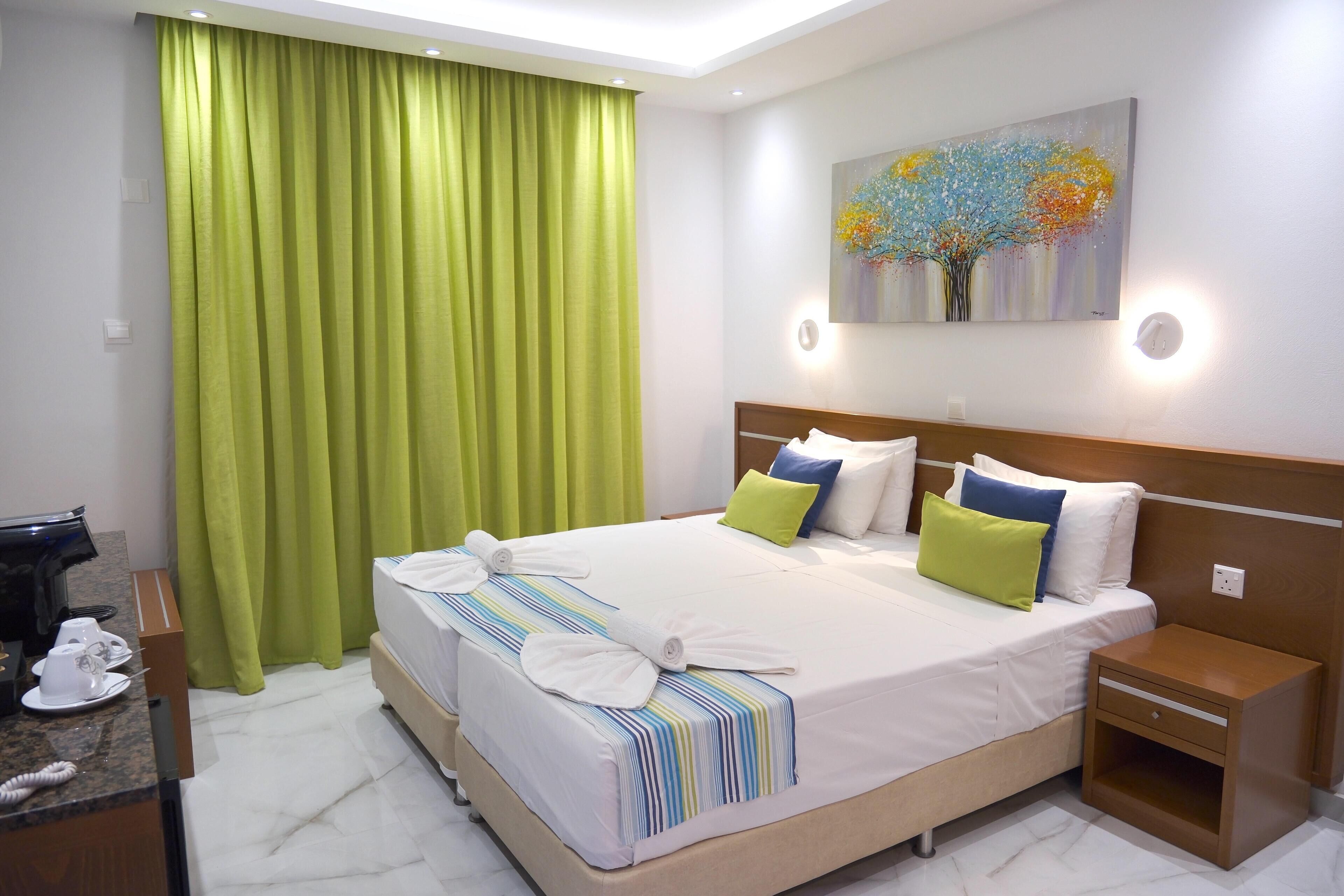 A hotel room with a large bed, a bedside table, a desk with a telephone, and a painting on the wall.