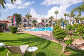 A pool area with lounge chairs, a small pool, and palm trees. - Loutsiana Hotel Apts (Ayia Napa)