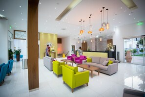A modern lobby with bright yellow walls, a reception desk, and colorful seating areas. - Loutsiana Hotel Apts (Ayia Napa)