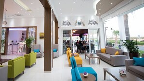 Um hall amplo com assentos modernos, uma área de recepção e grandes janelas com vista para o exterior.