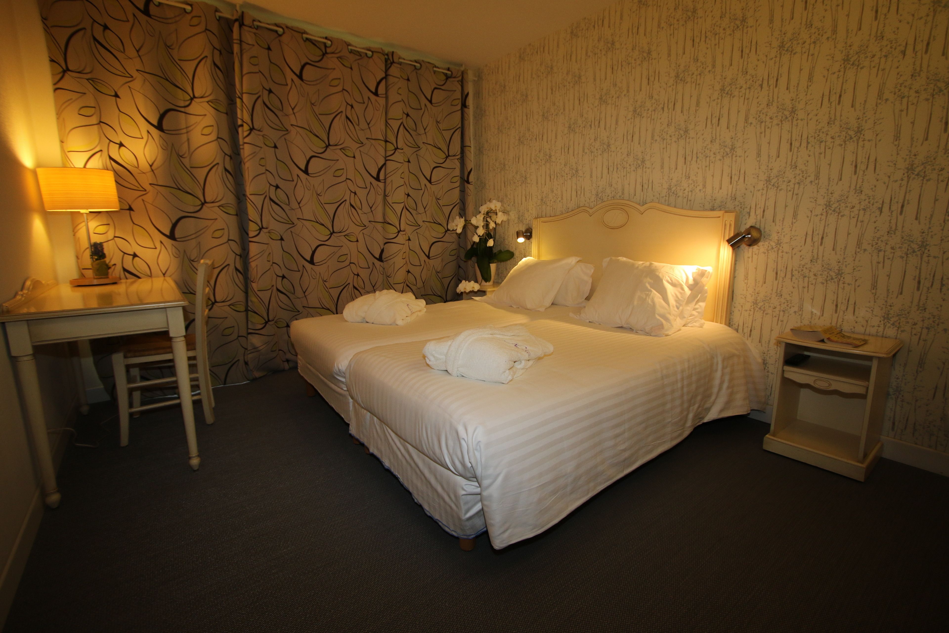 Una habitación de hotel con una cama grande, un escritorio con lámpara y una mesita de noche.
