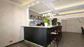 A modern kitchen with a central island, bar area, and seating. - Hotel Napoléon (La Turbie)