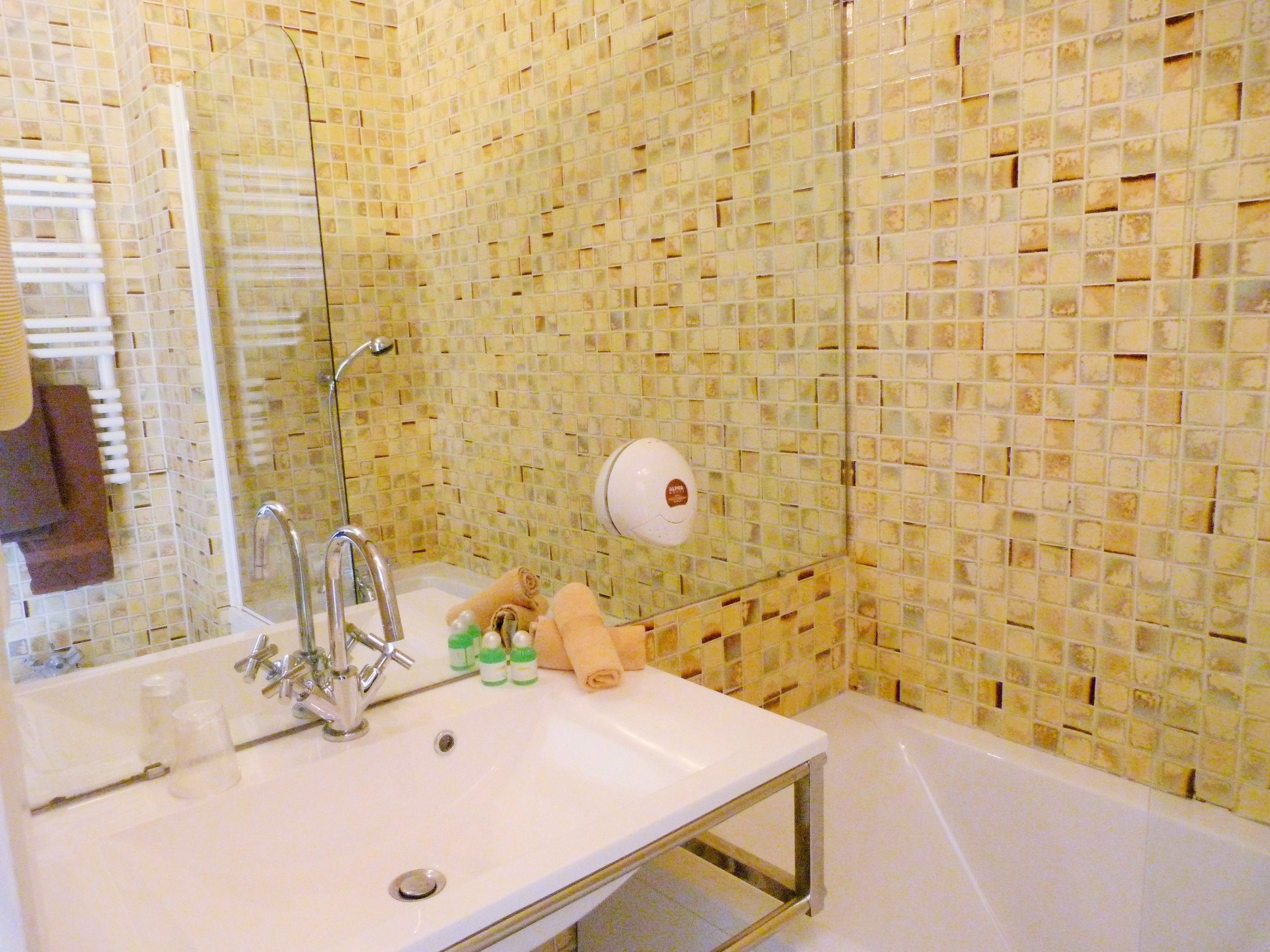 Un baño con lavamanos blanco, un espejo, toallero y zona de ducha.