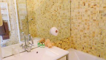 Un baño con lavamanos blanco, un espejo, toallero y zona de ducha.