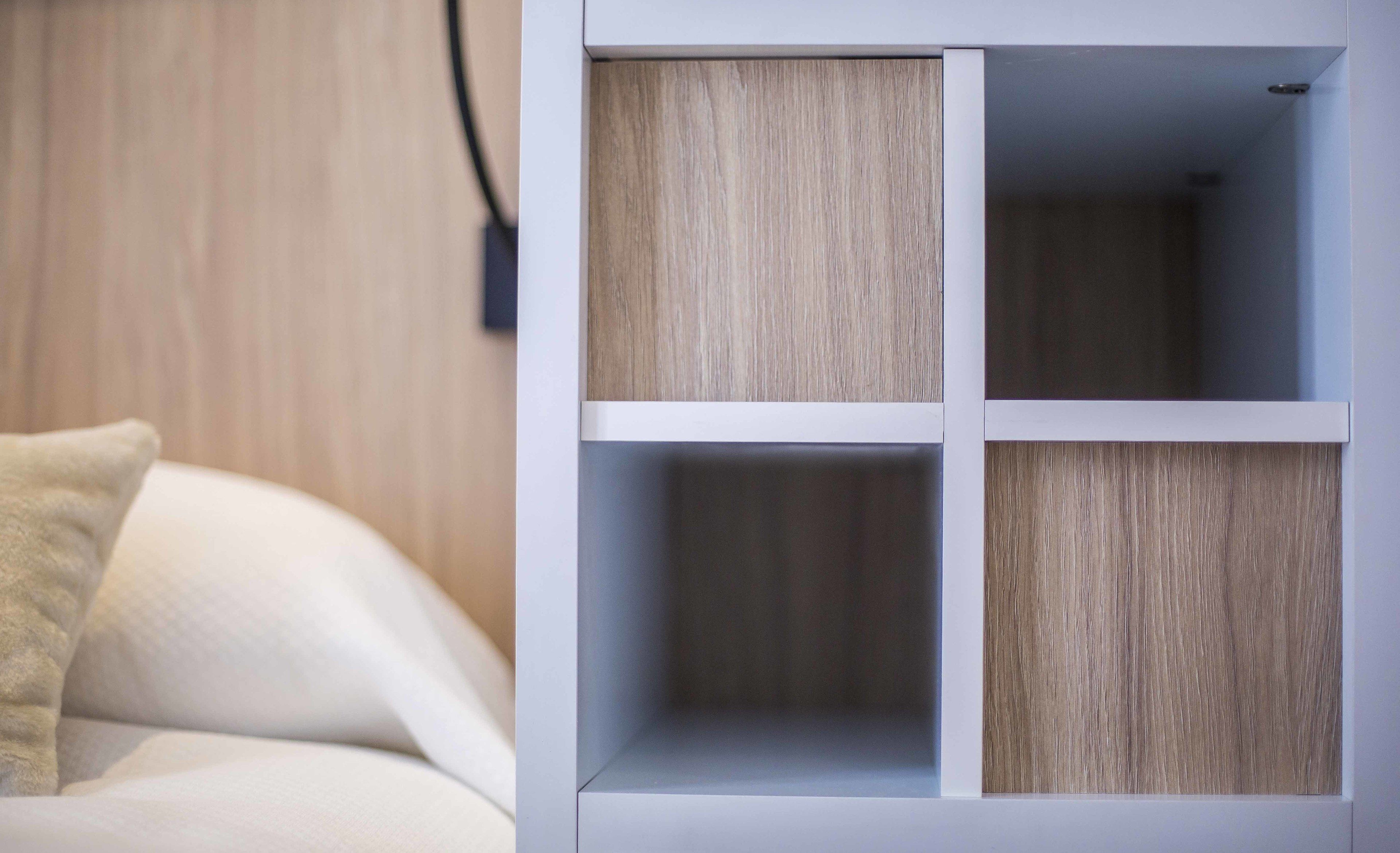 Een witte wandplank met vier vakken, elk voorzien van een houten paneel.