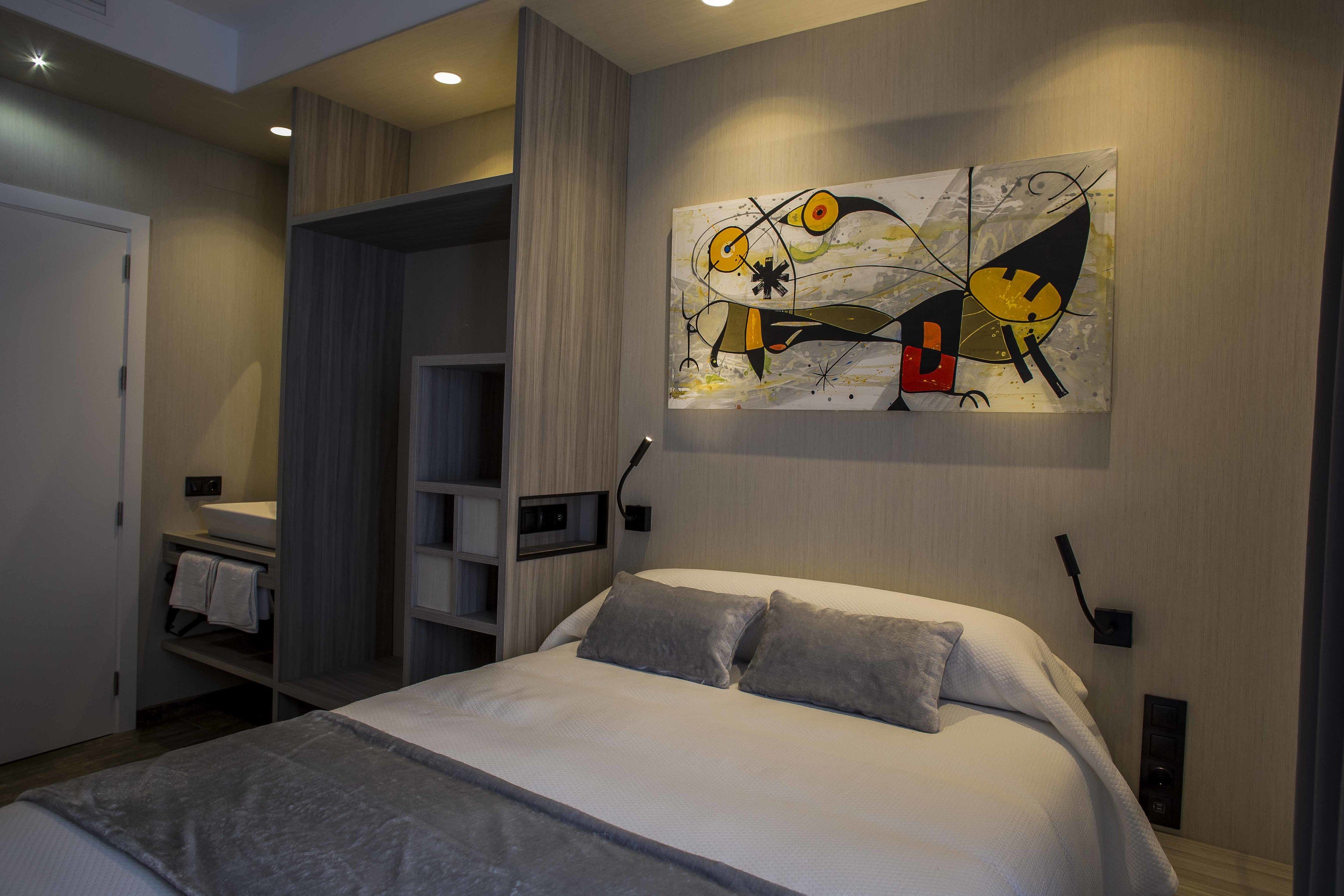 A modern bedroom with a bed, a built-in wardrobe, and a large abstract painting on the wall.