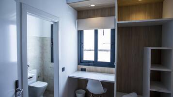 A modern bathroom with a toilet, sink, and a built-in desk with a chair.