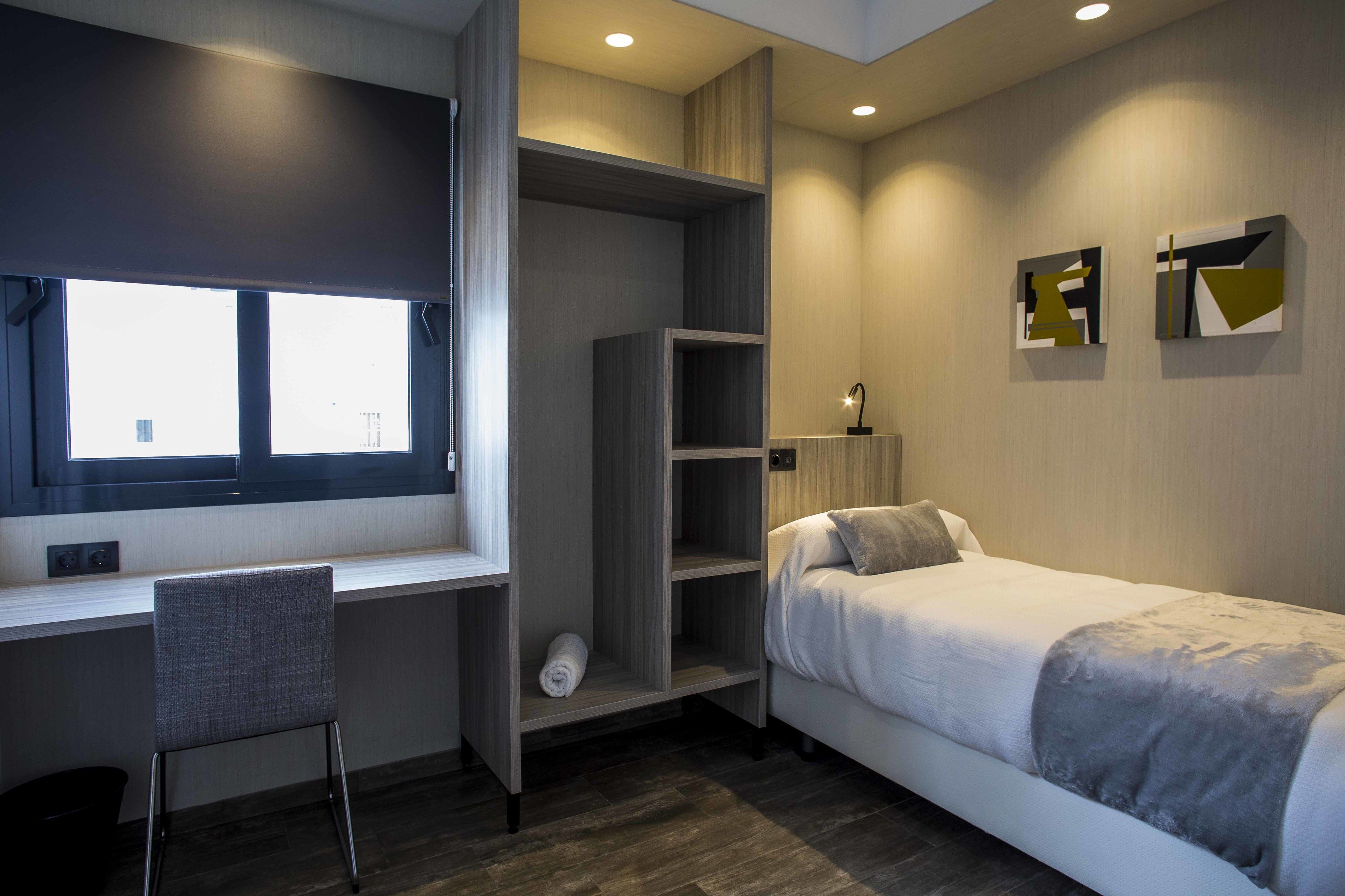 Una camera da letto moderna con un letto, una scrivania e una sedia.