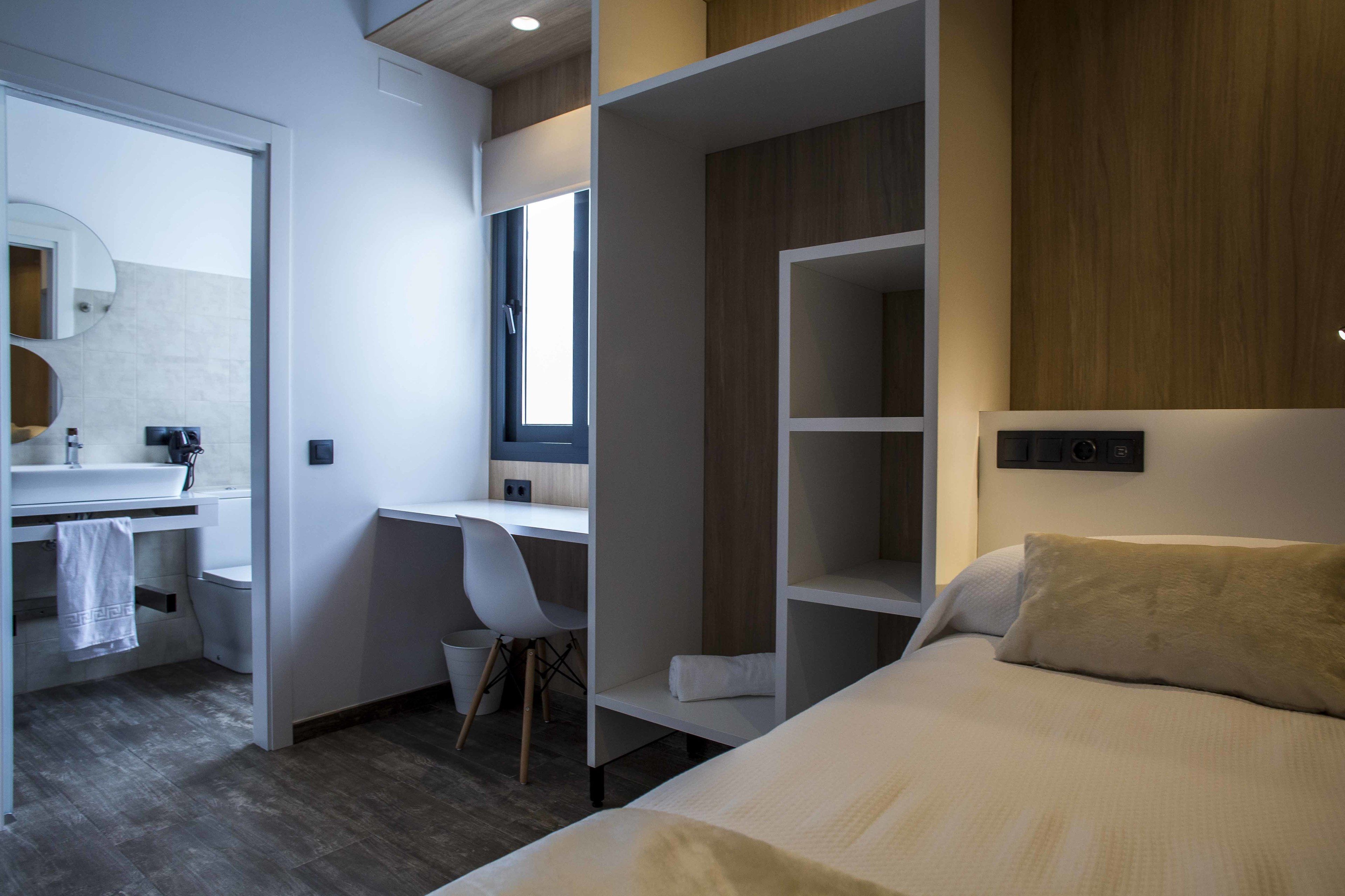 Une chambre d’hôtel moderne équipée d’un lit, d’un bureau, d’une chaise et d’une armoire.