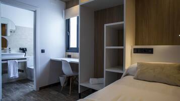 Une chambre d’hôtel moderne équipée d’un lit, d’un bureau, d’une chaise et d’une armoire.