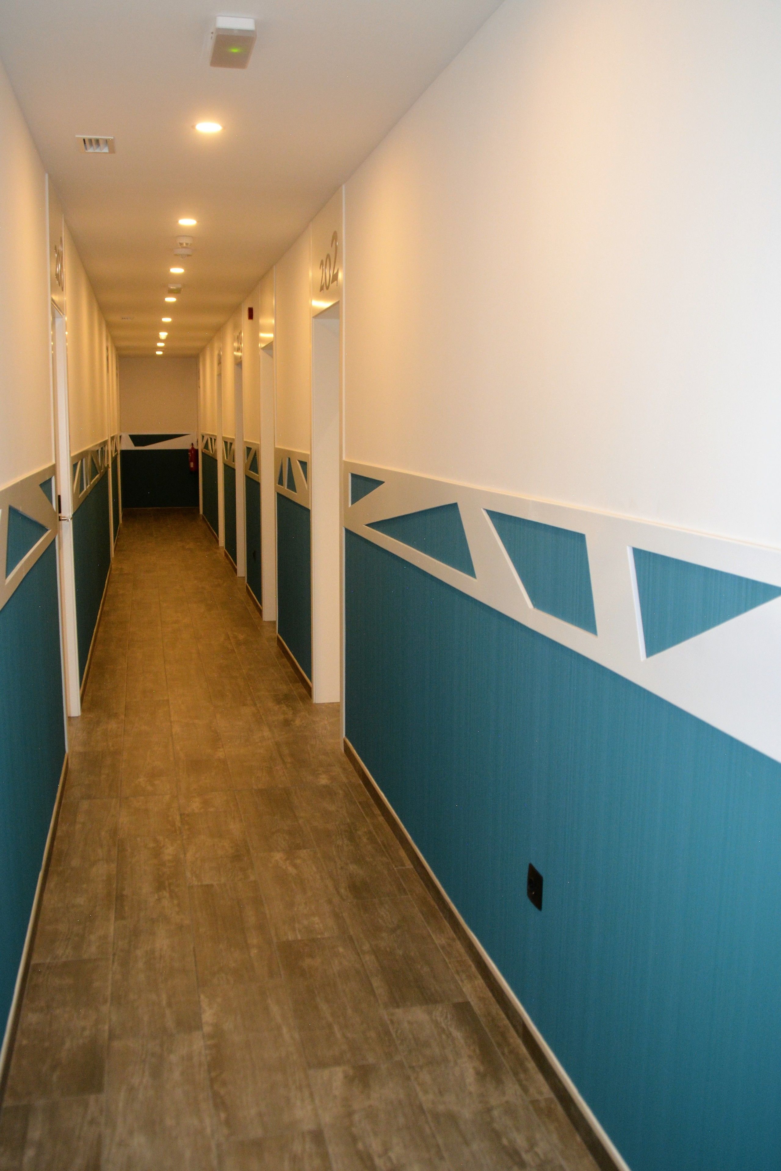 A long, narrow hallway with blue and white walls and a wooden floor.