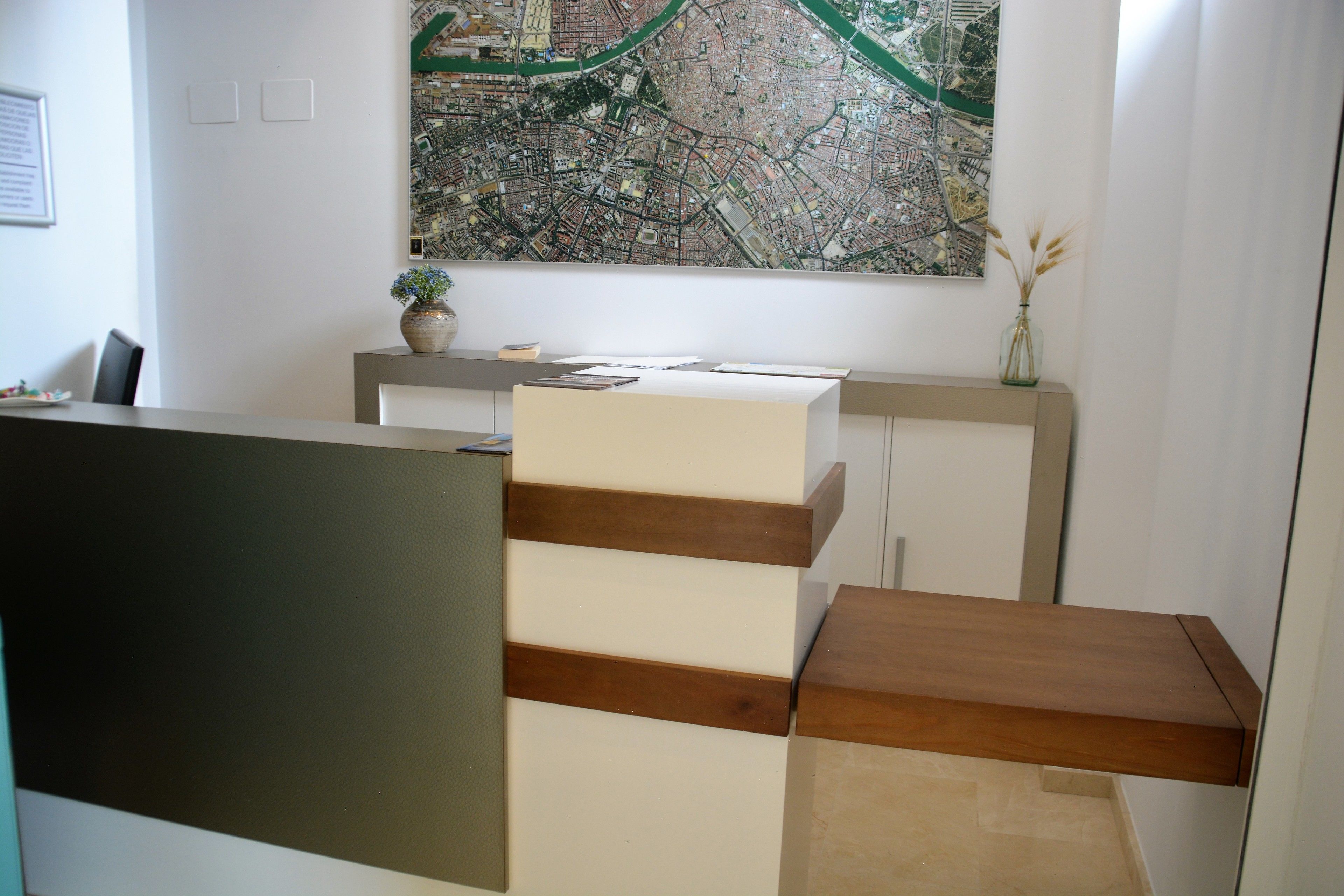 A modern office space with a desk, a map on the wall, and a vase with dried plants.
