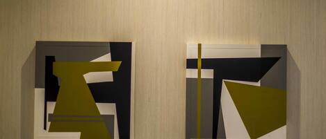 Two abstract paintings on a textured wall.