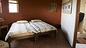Ein Zimmer mit einem Einzelbett, einem kleinen Tisch und einem Fenster.