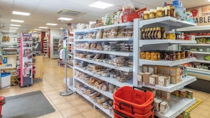 A grocery store with shelves stocked with various food items and a red shopping basket. - Hostal Rio Ara Bellosta (Fiscal)