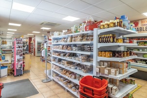 Un supermercado con estantes llenos de diversos productos alimenticios y una cesta de compra roja.