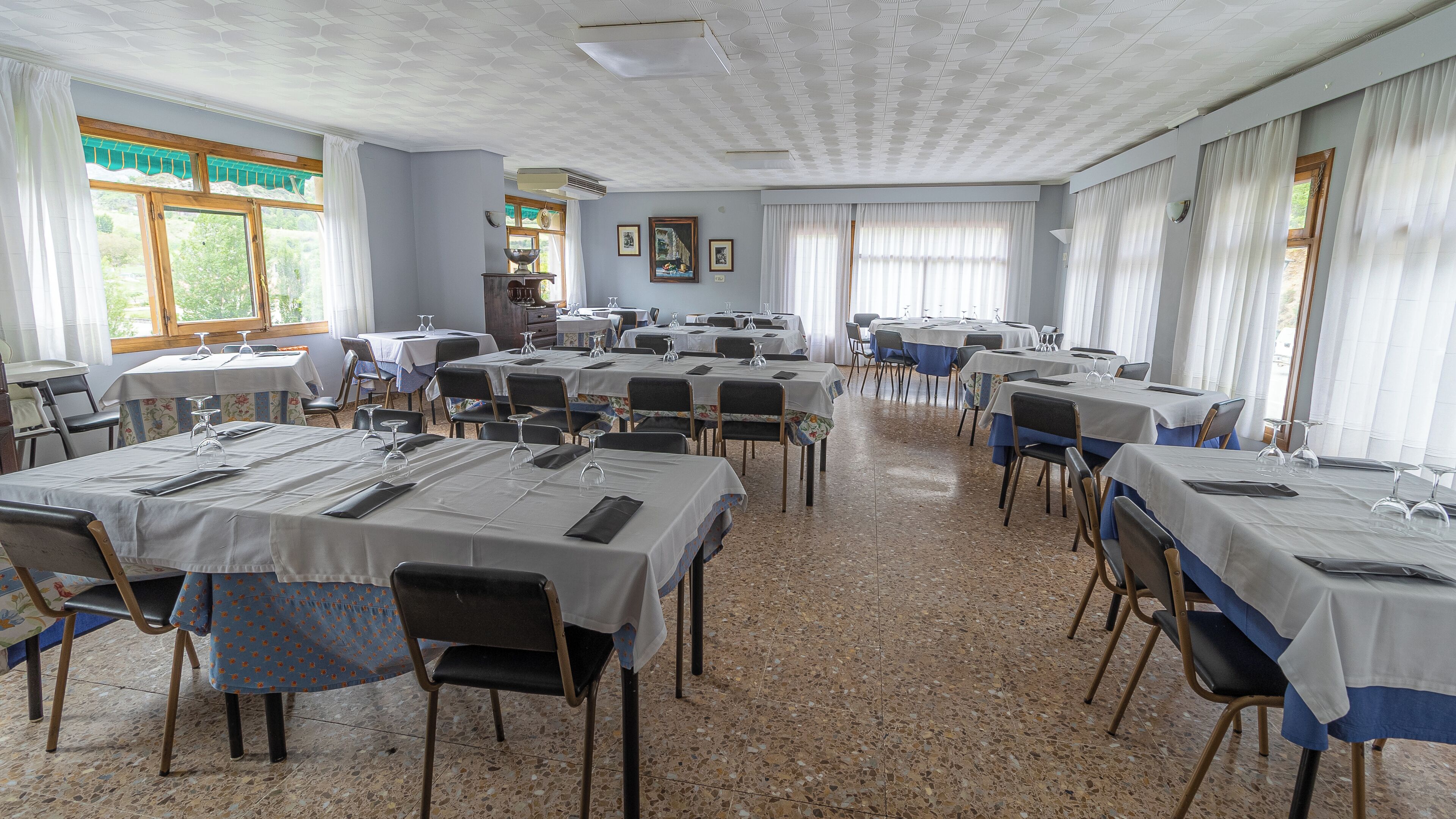 Ein Konferenzraum mit mehreren Tischen, Stühlen und einem gefliesten Boden.