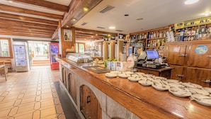 A restaurant interior with a wooden counter, tiled floor, and a variety of food items displayed. - Hostal Rio Ara Bellosta (Fiscal)