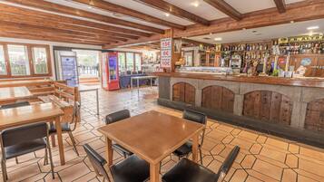 Un restaurante con mesas y sillas de madera, una zona de bar con una variedad de botellas y un cartel con el menú.