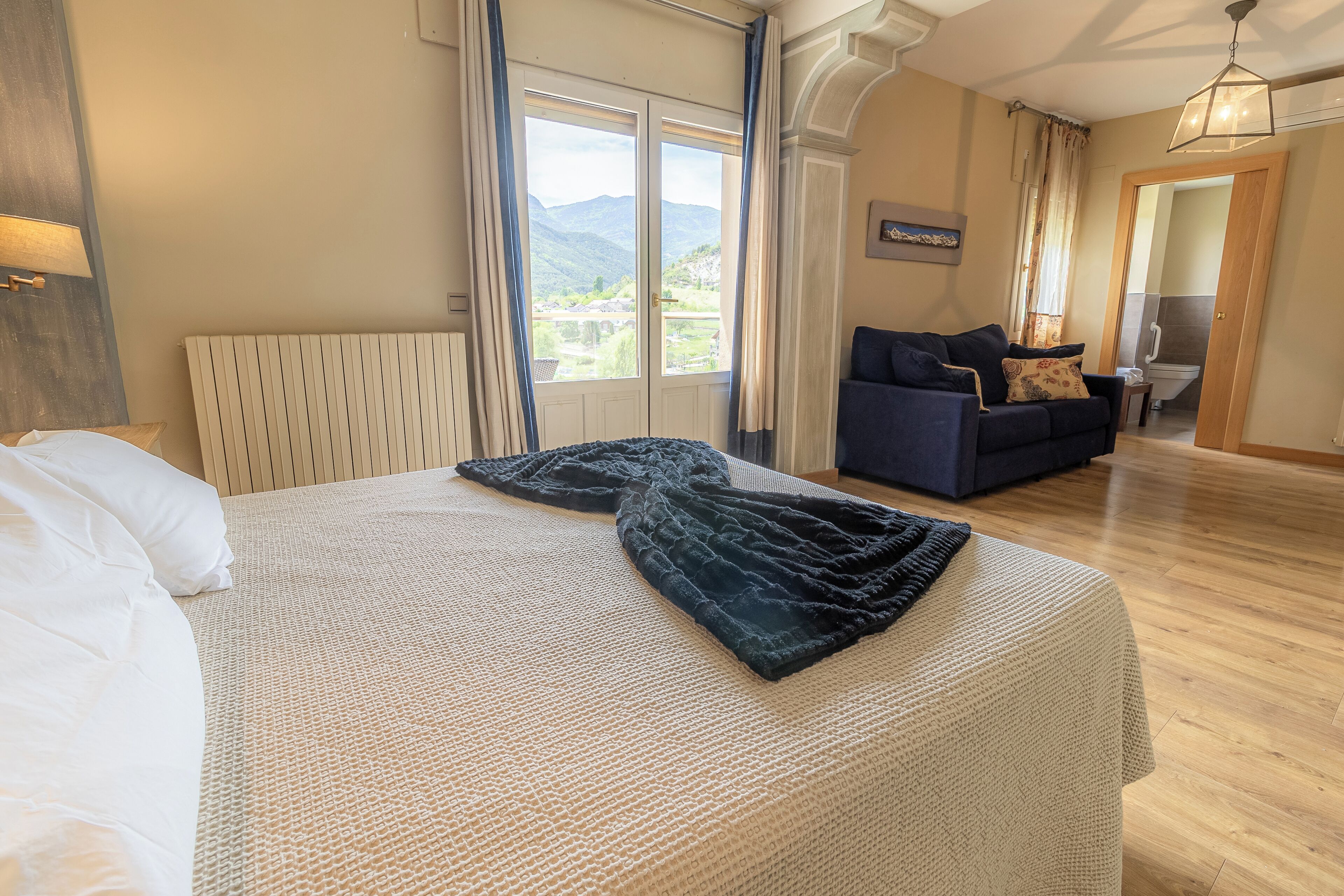 Une chambre avec un lit, un canapé et une vue sur les montagnes par la fenêtre.