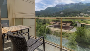 A balcony with wicker furniture overlooking a river and mountains. - Hostal Rio Ara Bellosta (Fiscal)