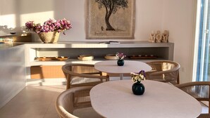 Une cuisine moderne avec des meubles en osier, un îlot central et un coin repas doté de tables rondes.