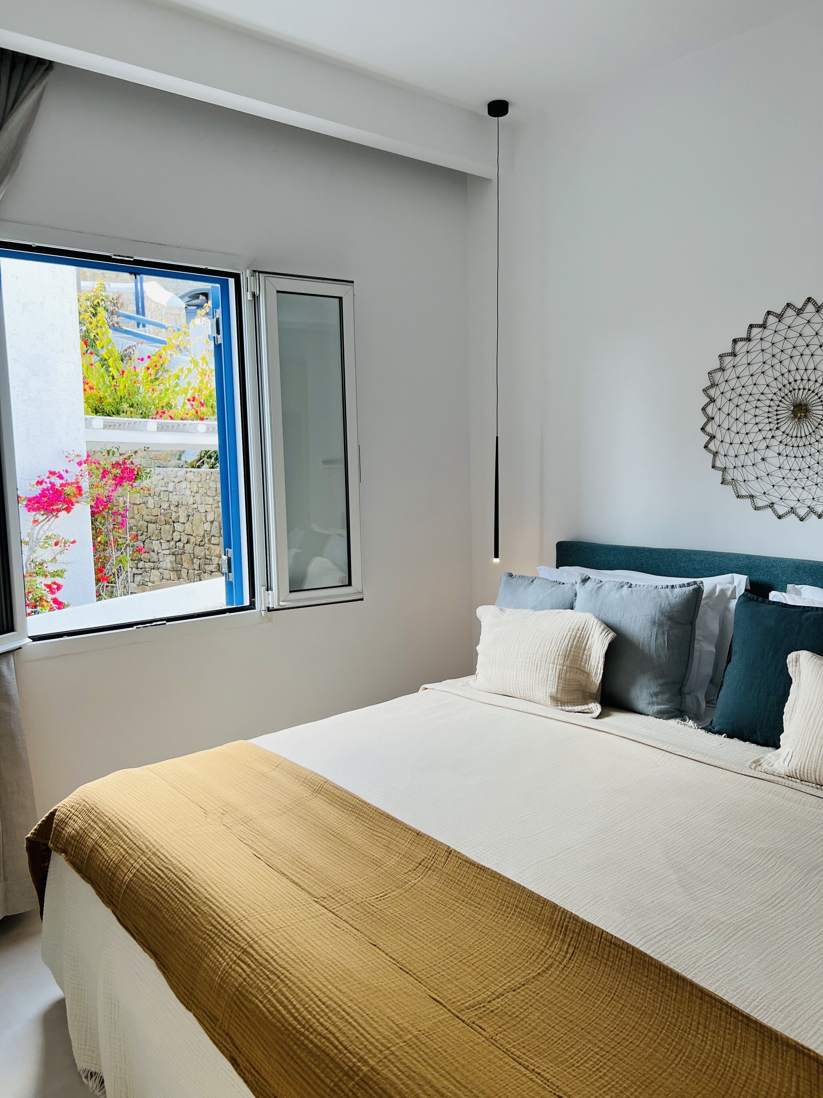A bedroom with a bed, a window, and a wall decoration.