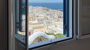 Une fenêtre donnant sur une ville côtière et la mer.
