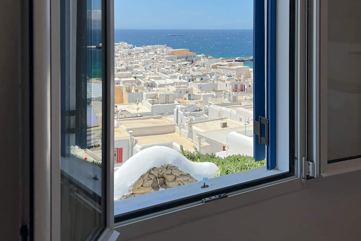 Une fenêtre donnant sur une ville côtière et la mer.