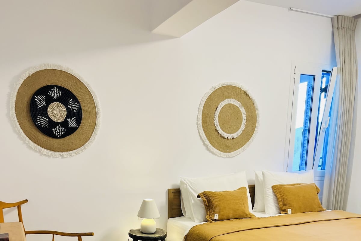 Une chambre à coucher comprenant un lit, des tables de chevet, une chaise et deux éléments de décoration murale.