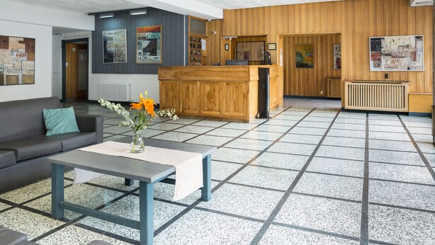 Un hall d’entrée avec un comptoir de réception, un canapé, une table basse et un sol carrelé.