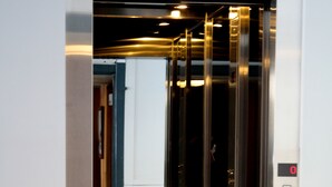 Un ascenseur avec un intérieur métallique et un écran numérique affichant le chiffre « 0 ».
