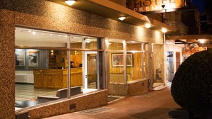 Façade d’un hôtel avec un espace d’accueil, de grandes fenêtres et une enseigne indiquant « HÔTEL PREMIER ».