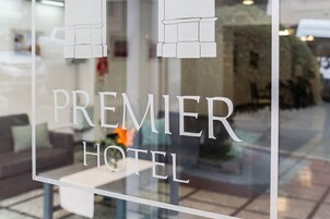 Un letrero de hotel con el nombre "Premier Hotel" y una ventana de vidrio que refleja el interior.