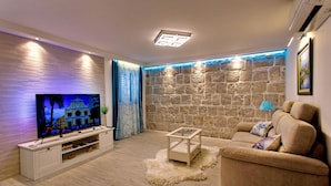A modern living room with a flat-screen TV, a beige sofa, a glass coffee table, and a stone accent wall. - House Sandra (Split)
