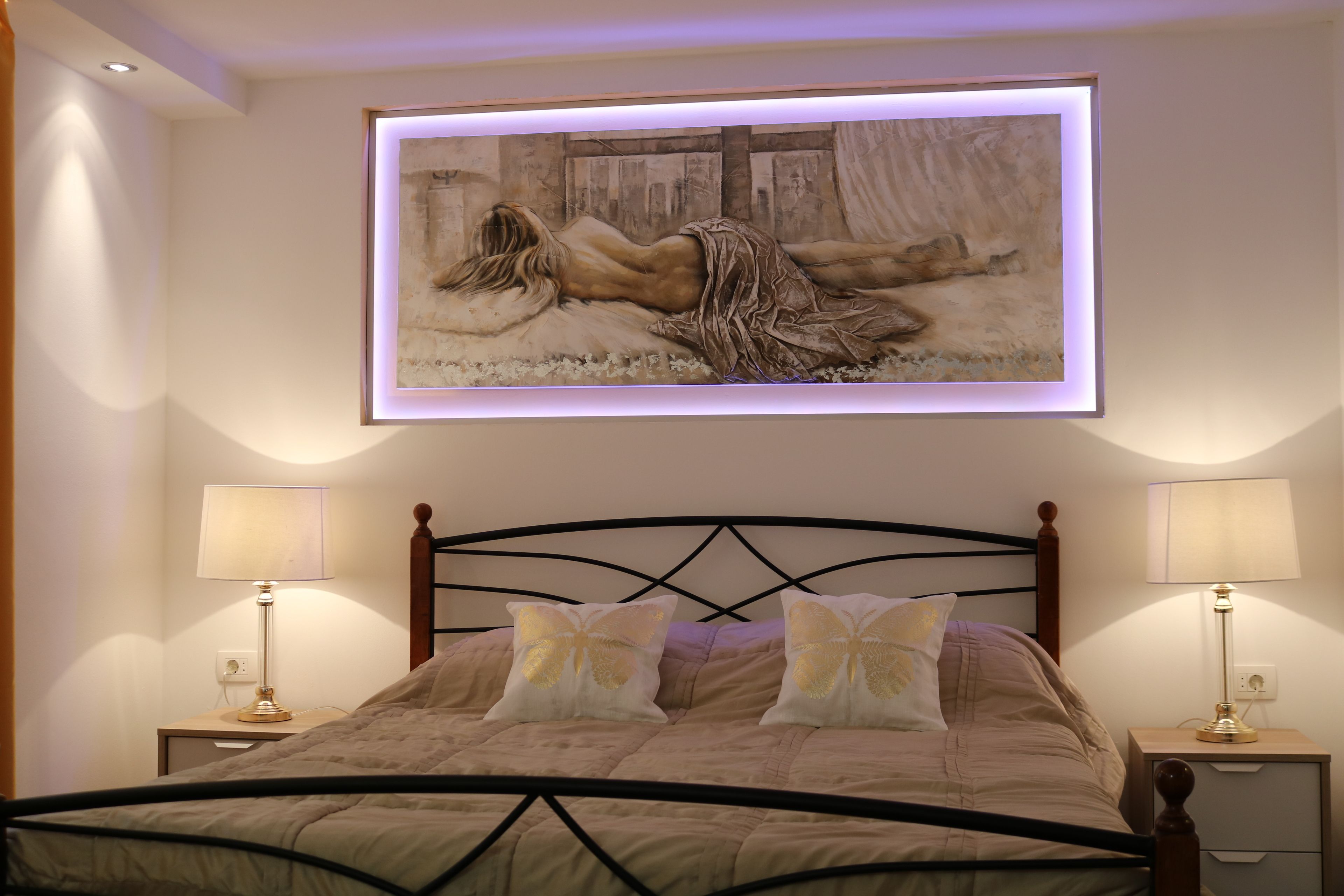 Ein Schlafzimmer mit einem Bett, zwei Nachttischen und einem großen, gerahmten Gemälde über dem Bett.
