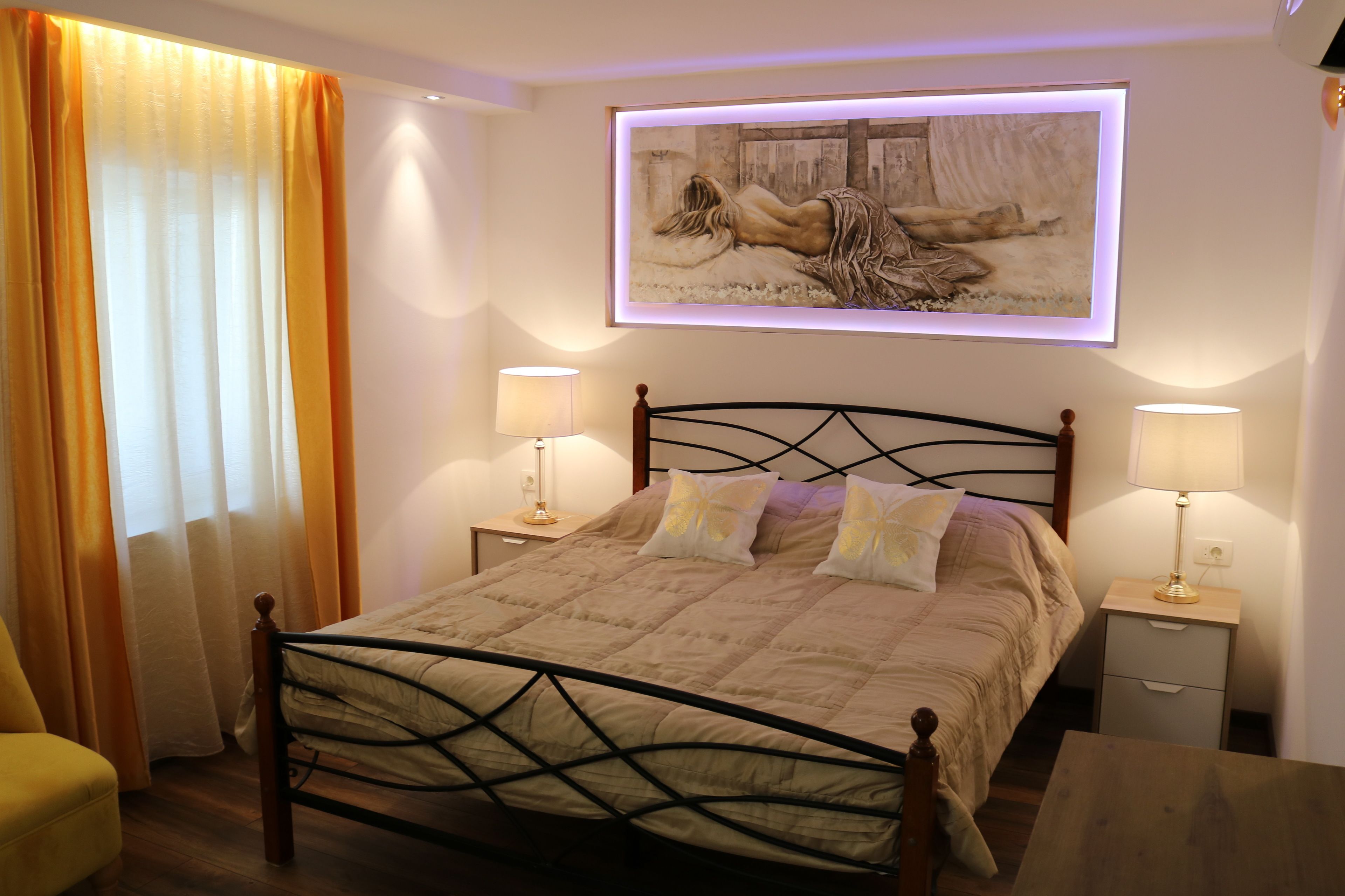 Een keurig opgemaakt slaapkamer met een bed, twee nachtkastjes, een stoel en een schilderij boven het bed.
