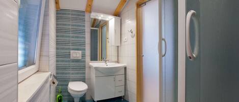 A bathroom with a toilet, sink, and shower.