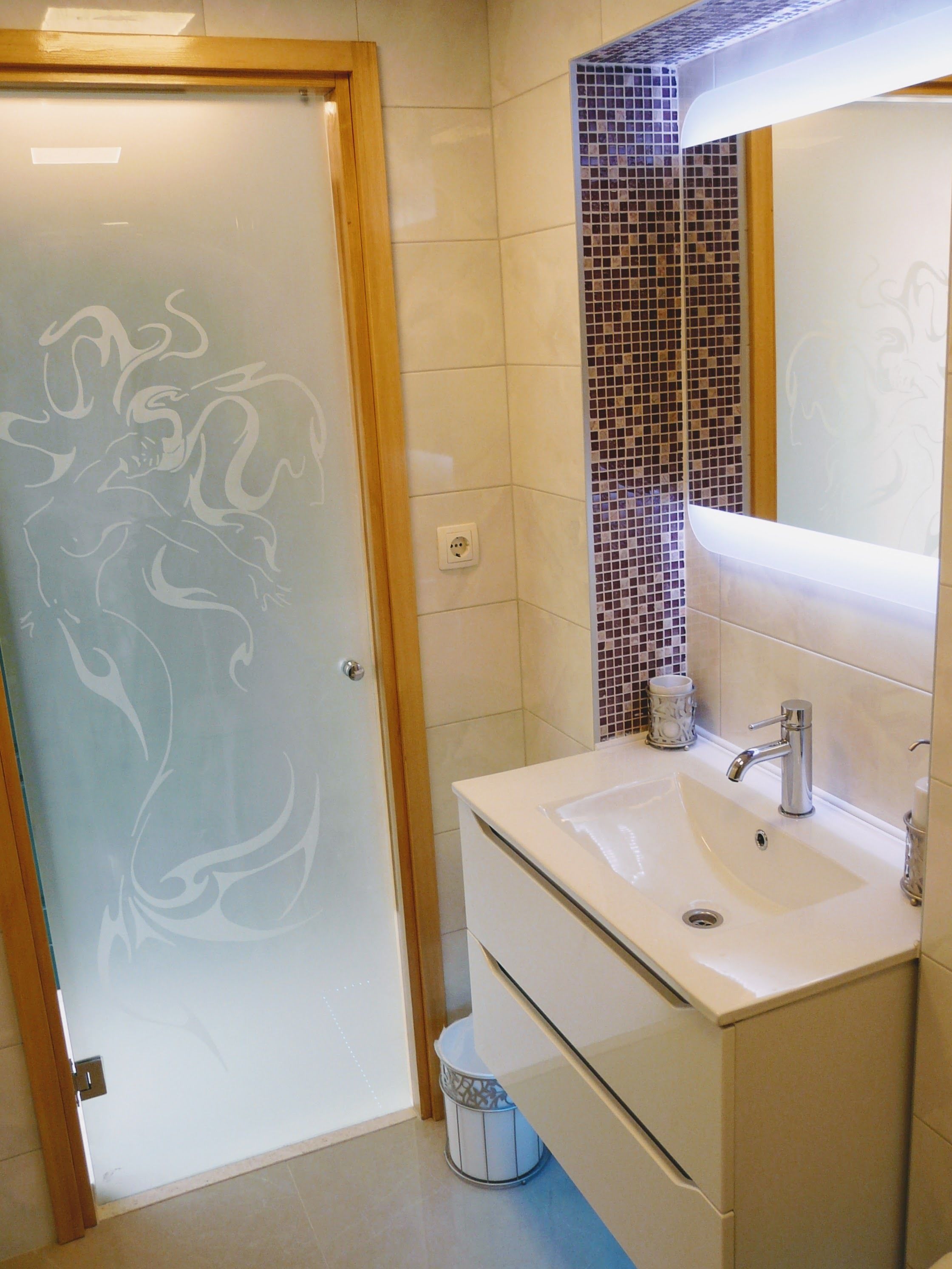 Un baño con lavamanos blanco, espejo y salpicadero de azulejos.